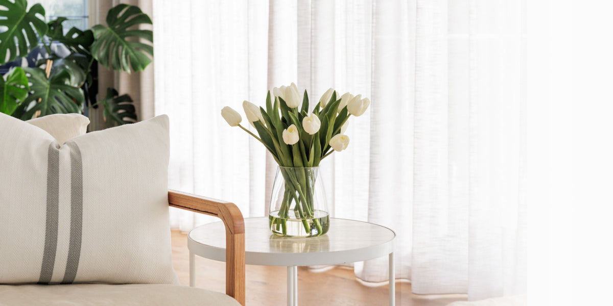 White tulip silk flower arrangement in glass vase positioned on coffee table in Australian home